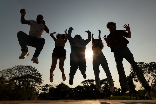 Siluetas de amigos de tiro completo saltando al atardecer