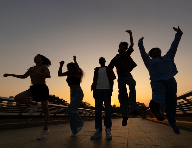 Siluetas de amigos de tiro completo saltando al atardecer