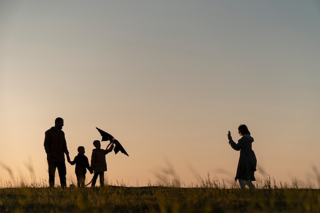 Siluetas familiares divirtiéndose al atardecer tiro completo