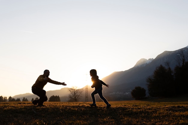 Foto gratuita siluetas de familias en la naturaleza al atardecer.