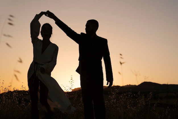 Siluetas de pareja bailando en la naturaleza tiro completo