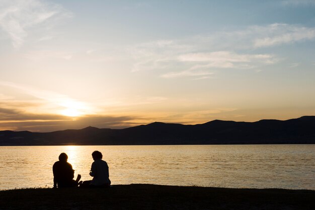 Siluetas de personas y la playa durante el atardecer