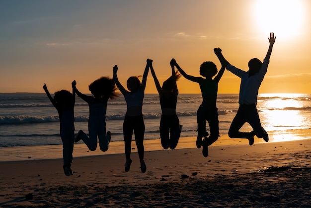 Siluetas de tiro completo de personas saltando al atardecer