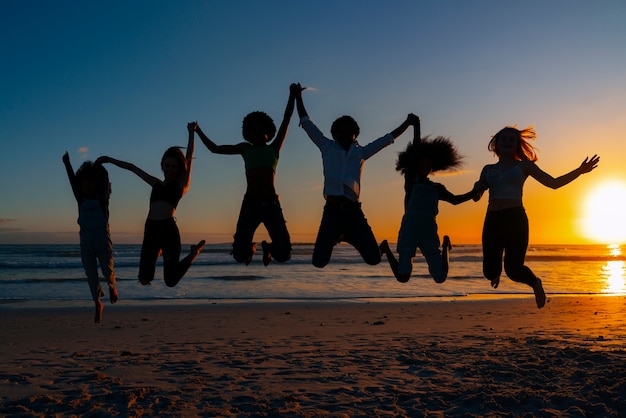 Foto gratuita siluetas de tiro completo de personas saltando al atardecer