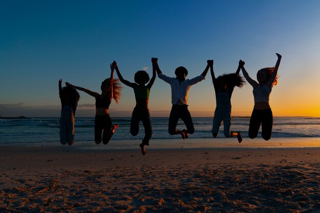 Siluetas de tiro completo de personas saltando al atardecer