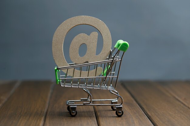 Símbolo de madera @ en carrito de la compra, concepto de compras en línea