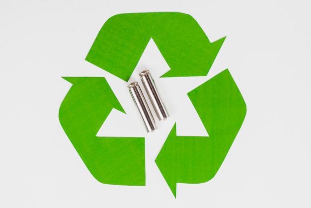 Símbolo de reciclaje ecológico verde y pilas usadas.