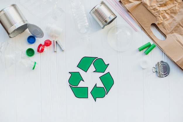 Símbolo de reciclaje con material de desecho en mesa de madera