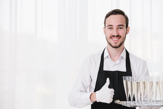 Sirviente feliz llevando copas de champán con espacio de copia