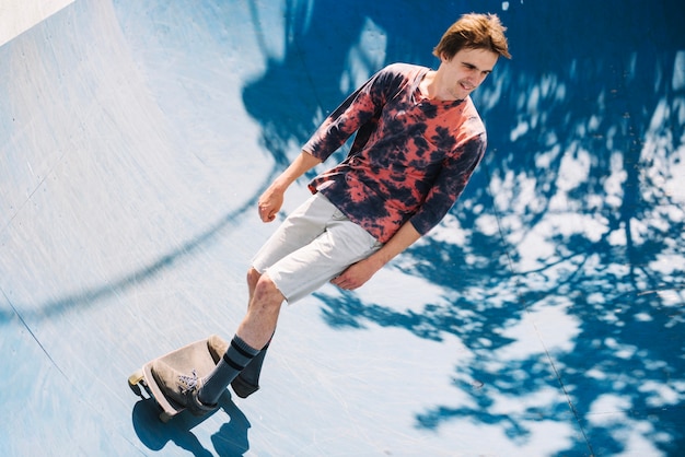 Skater alegre montando en skatepark