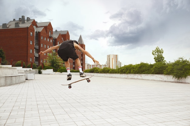 Skater haciendo un truco en la calle de la ciudad en un día nublado