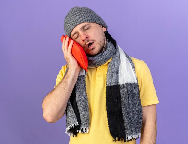 Sleepy joven rubio enfermo eslavo hombre vestido con bufanda y gorro de invierno