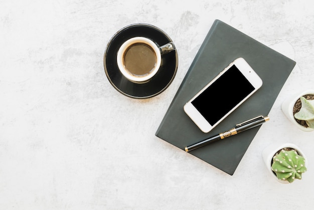 Smartphone y café en mesa con notebook