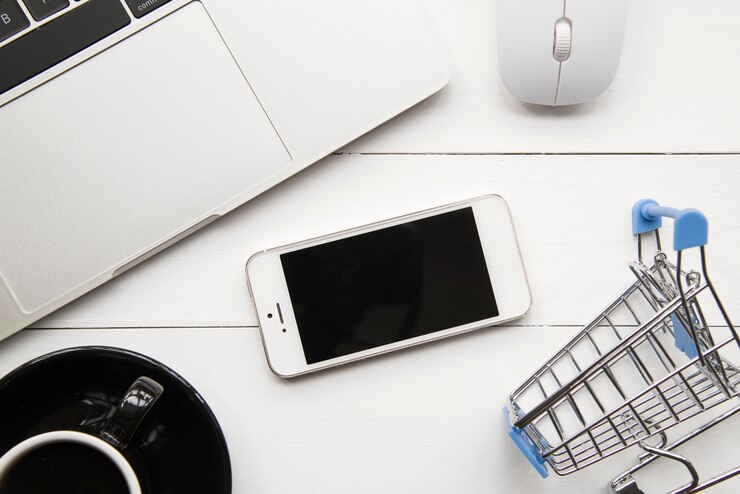 Foto gratuito smartphone cerca de laptop y carrito de compras