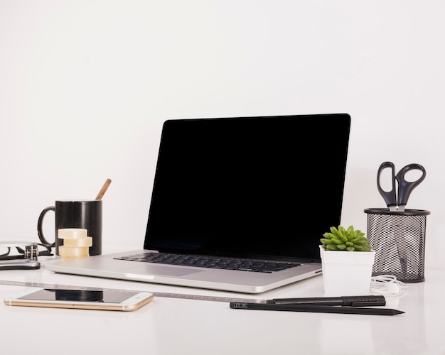 Smartphone y computadora portátil con la pantalla negra en blanco en el escritorio de oficina