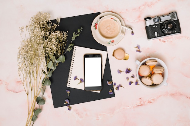 Smartphone con galletas, cámara y taza de café en la mesa