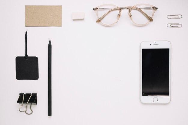 Smartphone y lindos anteojos cerca de escritorio