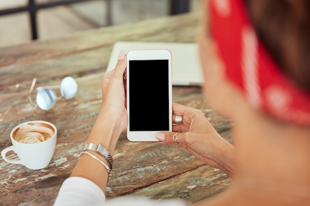 Smartphone en manos de mujer en café