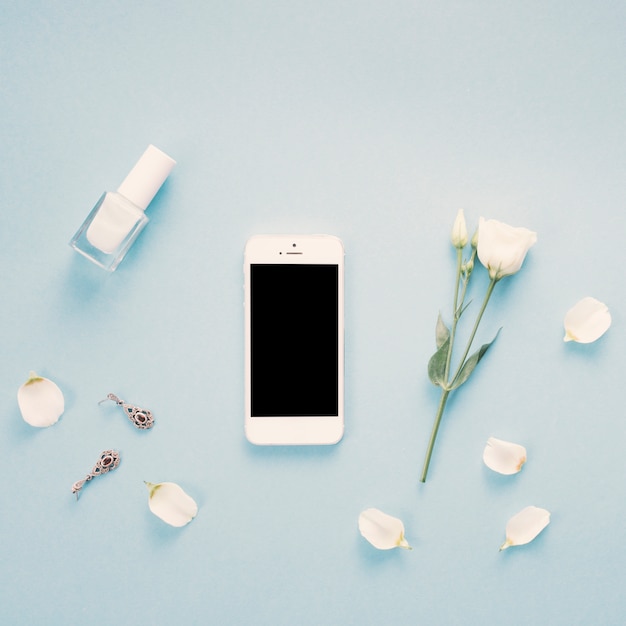 Smartphone con pantalla en blanco y flores en la mesa