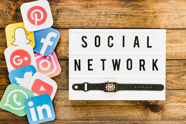 Smartwatch con iconos de redes sociales sobre la mesa de madera