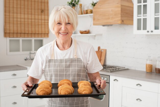 Smiley anciana sosteniendo la bandeja con croissants