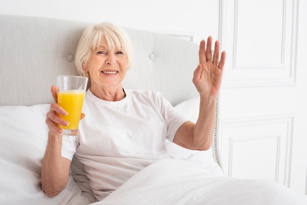 Smiley anciana sosteniendo un vaso con jugo