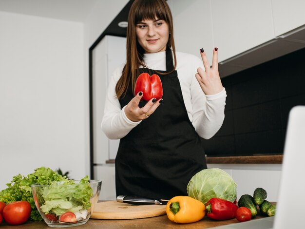 Smiley blogger femenina streaming cocina con portátil