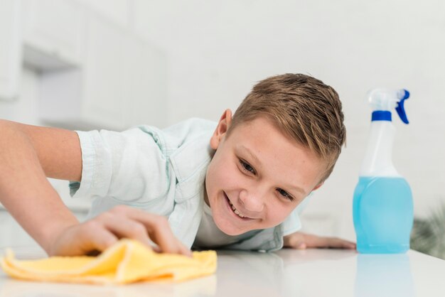 Smiley boy limpiando la mesa con un trapo