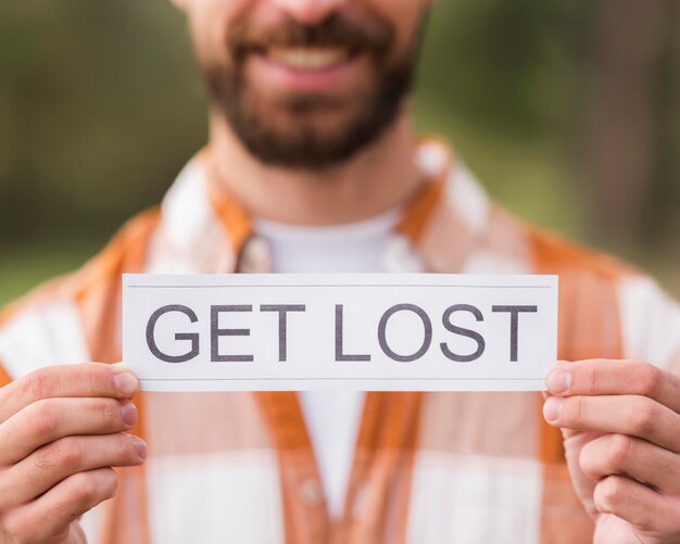 Smiley defocused man holding get lost sign