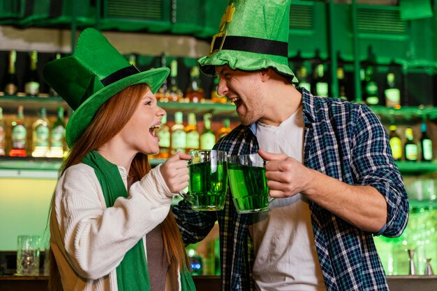 Smiley hombre y mujer celebrando st. día de patricio con bebidas