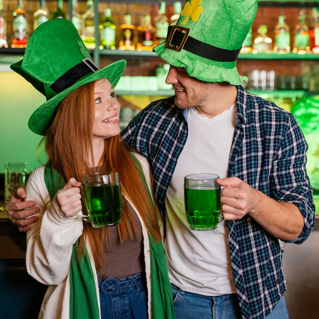 Smiley hombre y mujer celebrando st. patrick's day en el bar con bebida