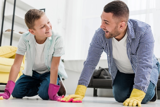 Smiley hombre y niño limpiando el piso