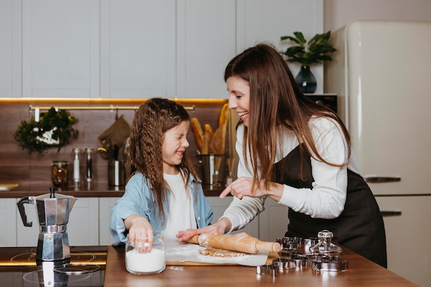 Smiley madre e hija cocinando en la cocina de casa