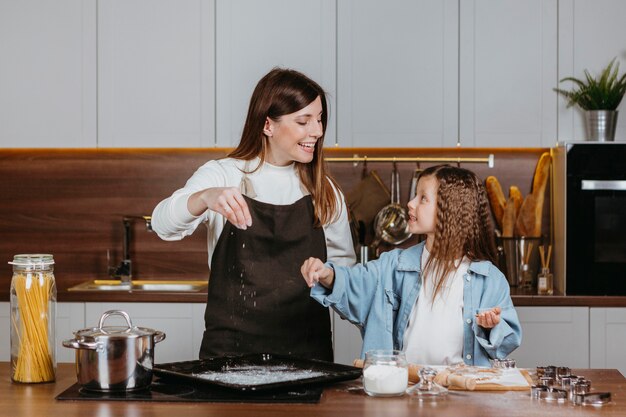 Smiley madre e hija cocinando juntos en la cocina de casa