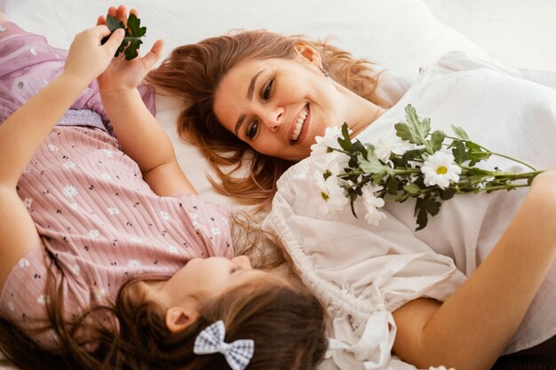 Smiley madre e hija con ramo de delicadas flores de primavera