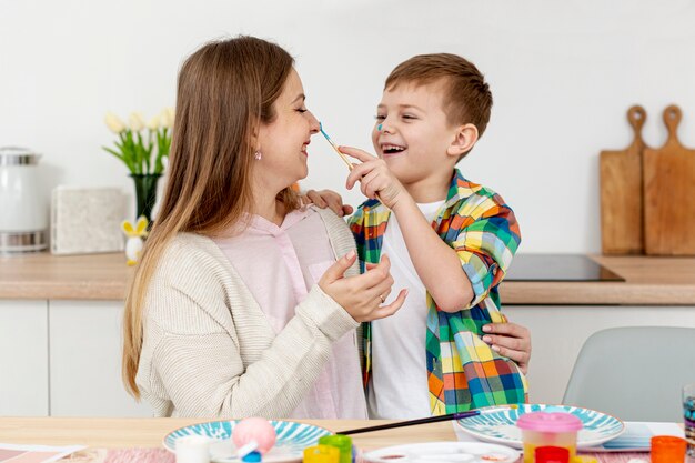 Smiley madre e hijo pintando huevos