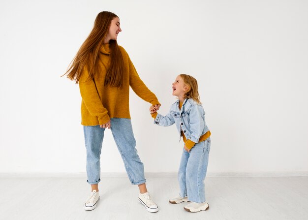 Smiley madre y niña en estudio full shot