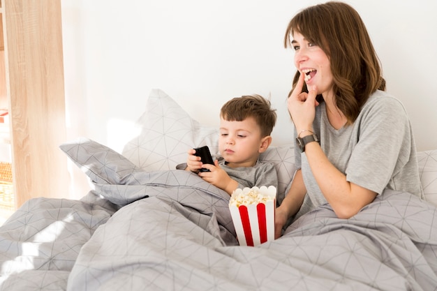 Foto gratuita smiley mamá e hijo comiendo palomitas de maíz