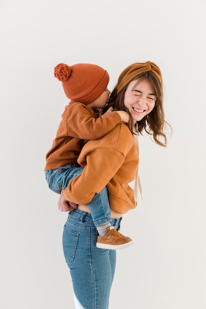 Foto gratuita smiley mamá con hijo en piggy back ride