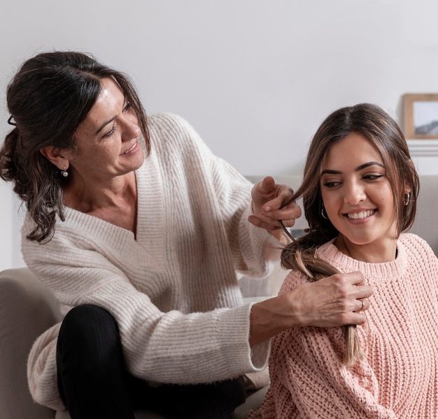 Smiley mamá trenzando hija cabello