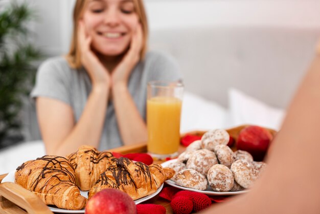 Smiley mujer borrosa siendo sorprendida con el desayuno en la cama