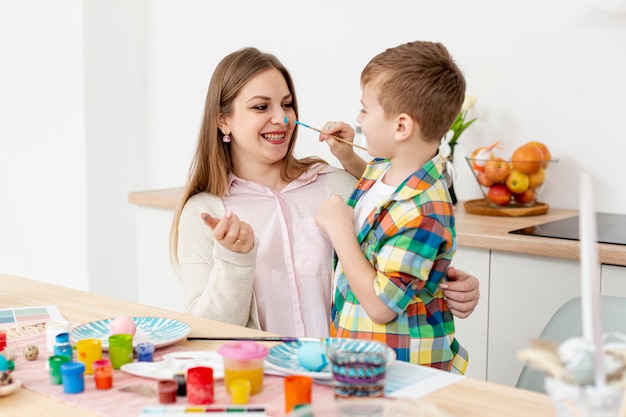 Smiley mujer e hijo pintando huevos