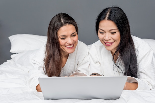 Smiley mujeres en cama usando laptop