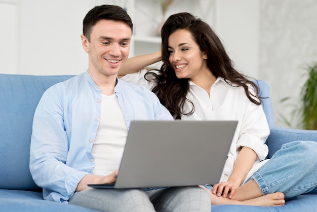 Smiley pareja en casa en el sofá con el portátil