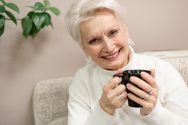 Smiley senior femenino en casa tomando café