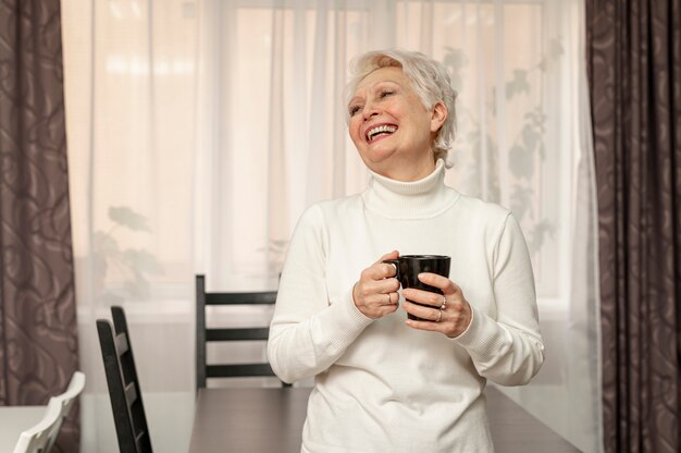 Smiley senior femenino sosteniendo la taza de café