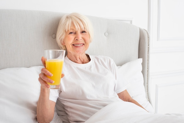 Smiley senior sosteniendo un vaso con jugo