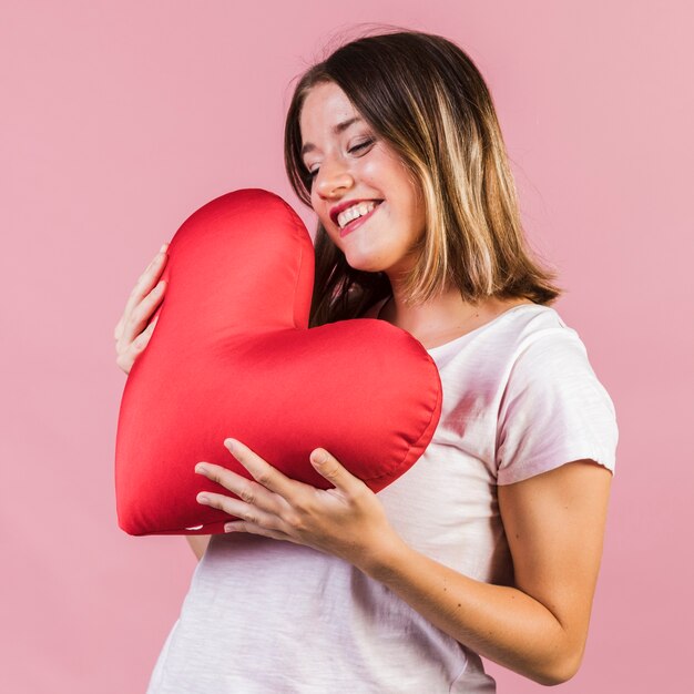 Smiley sosteniendo una almohada en forma de corazón