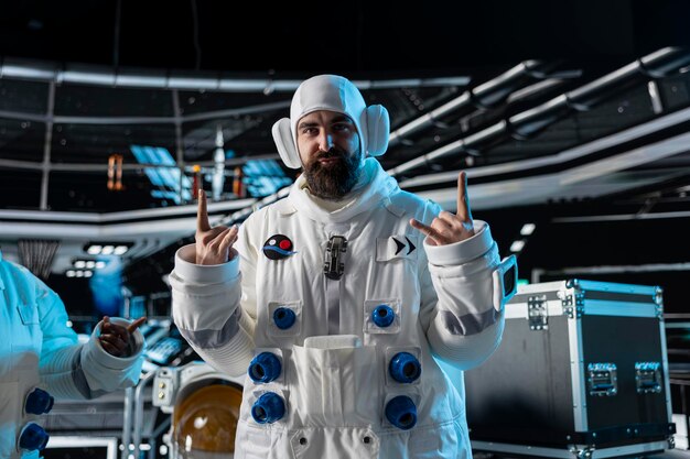 Smiling astronaut doing playful hand gestures inside space station
