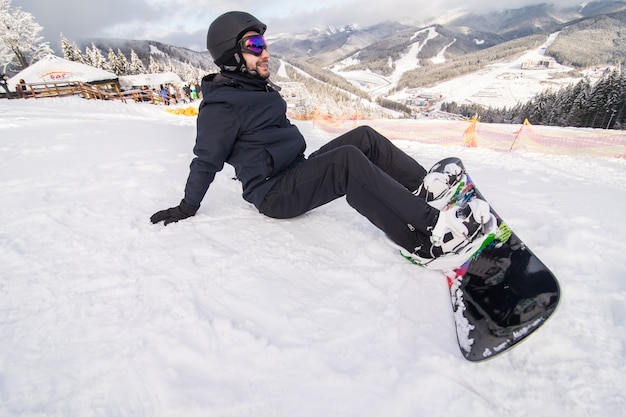 Snowboarder en la colina botones de sujeción antes de montar en la colina de nieve